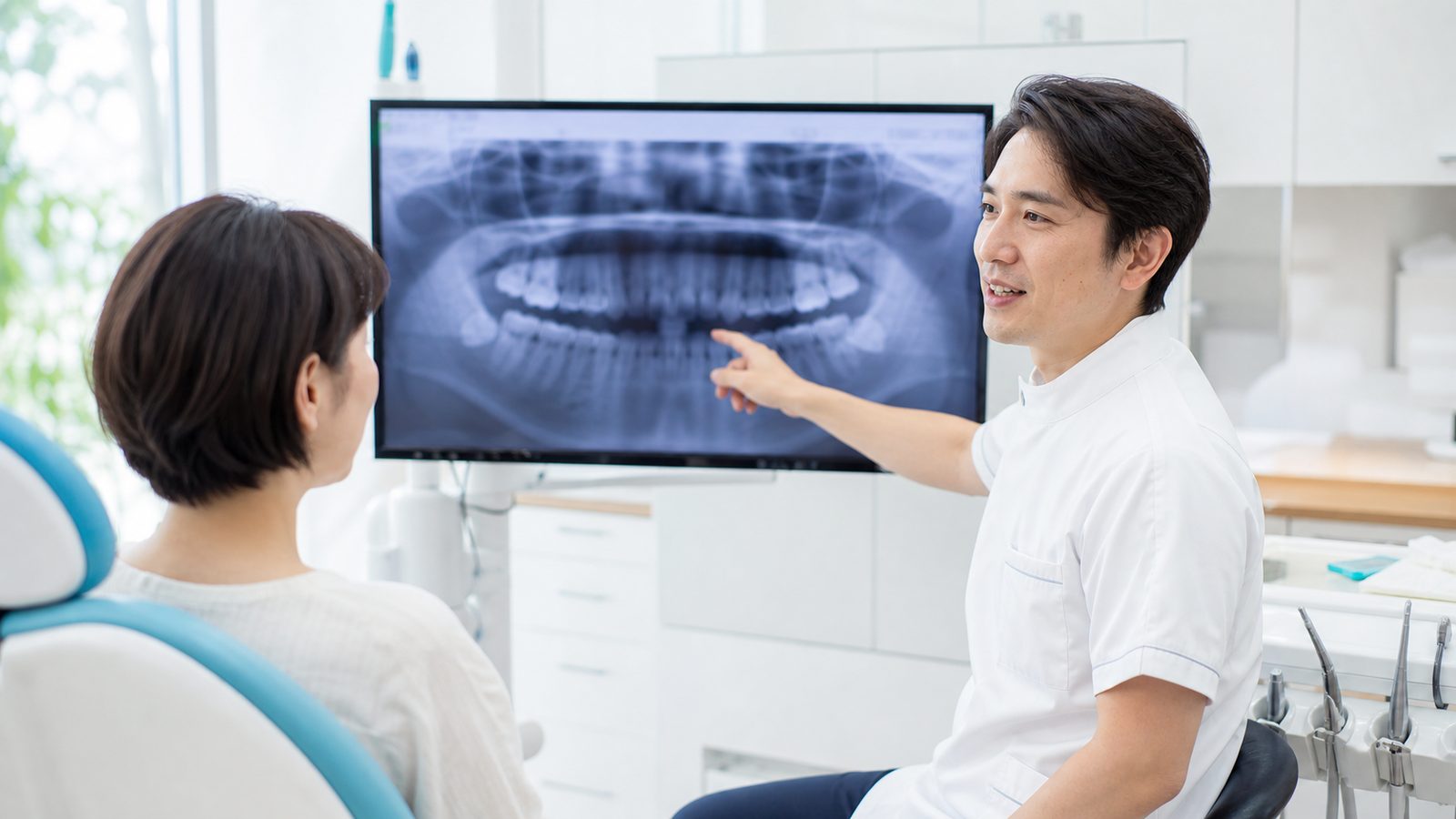 モニターのレントゲン画像を示しながら、治療方針をわかりやすく説明する歯科医師